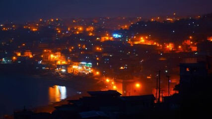 Poster - A nighttime view of a city from a hill, with buildings and streets lit up