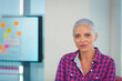 © WavebreakMediaMicro - Woman standing in office wearing pink-blue plaid shirt with planning board and window, copy space