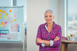 © WavebreakMediaMicro - Senior woman standing at office before whiteboard with charts and desk with colored pencils