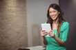 © WavebreakMediaMicro - Asian woman smiling and holding white tablet at home office with documents on table, copy space