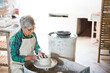 © WavebreakMediaMicro - Senior female potter in apron shaping clay vessel on pottery wheel in ceramics studio, copy space