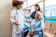 © unai - Doctor and nurse supporting senior woman in wheelchair at hospital