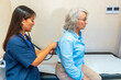 © unai - Doctor using stethoscope examining elderly woman in hospital room