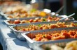 © Viktor - Outdoor catering event of Mexican food served in aluminum trays. Buffet setup of ready-to-eat dishes. Dishes includes fajitas, sauces, chicken, rice, beans. Summer party catering concept.