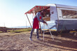 © Wavebreak Media - African American man in red apron positioning signboard beside trailer on coastal lot, copy space