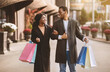 © Prostock-studio - Walking in city for two and shopping in mall. Smiling millennial african american husband and wife in coats with color bags have fun after final sale and Black Friday in store, outdoor, copy space