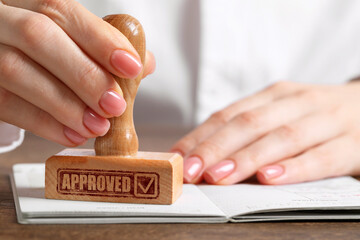 Fototapete - Approved. Woman stamping passport at table, closeup