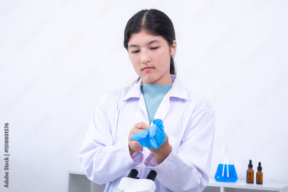 Teen girl in white coat wearing gloves before research task in a modern ...