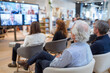 © Anastasiia Havelia - Corporate webinar in progress, group watching screen with digital content, modern interior, focus on inclusivity