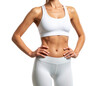 © TransPicHub - A fit woman in white athletic wear stands with hands on hips, showcasing toned abs and an athletic physique.