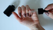 © Lesia - A woman's hand drips oil into her finger with a pipette. Nails are covered with manicure. Light brown color. White background. A small black bottle lies outside the hand. White hands. Macro photo.