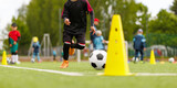 Young Soccer Player Dribbling Ball Through Yellow Training Cones During Youth Practice on Outdoor Field