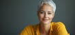 © Vergiliy - Smiling woman with short white hair wearing yellow shirt against gray background