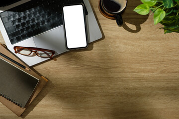 Wall Mural - Creative desk including laptop, mobile phone with blank screen, and planner in natural lighting.