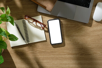 Wall Mural - Creative desk including laptop, mobile phone with blank screen, and planner in natural lighting.