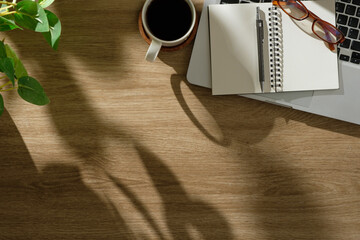 Wall Mural - Cozy workspace with laptop, notebook, glasses, and coffee cup on a wooden desk.