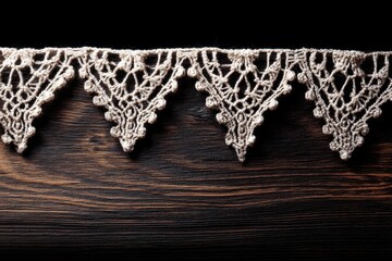 Poster - Delicate handmade crochet lace border elegantly rests on a dark textured wooden surface, creating a beautiful contrast and showcasing the intricate design.