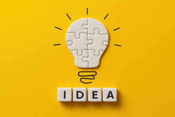Poster - A conceptual shows the process innovation through a puzzle forming a light bulb above the word idea symbolizing work and strategy