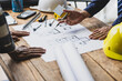 © Wasan - Architects discussing at architectural plans on a table. Architect and contractor engineer working together in office.