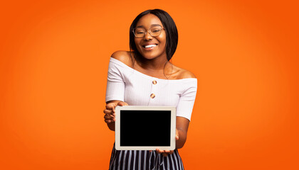 Poster - Great Application. Smiling Afro Girl Showing Digital Tablet With Blank Screen Standing In Studio Over Orange Background. Panorama, Mockup