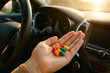 © smth.design - Person holding assorted pills inside a car, highlighting medication awareness and safety concerns during driving at sunset