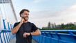 © Home-stock - Handsome athlete man training outdoors on bridge, runner using earphones and smartwatch for health data and statistics, panorama, free space
