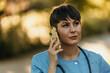 © La Famiglia - Medical worker talking on the phone in a sunny park setting