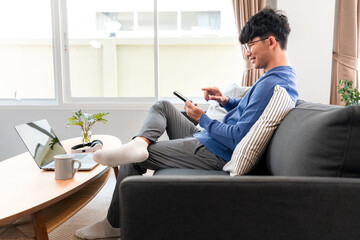 Poster - Asian man in casual clothes, using smartphone to working about business project from home and checking social media