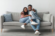 © Prostock-studio - Happy laughing relaxed millennial African American woman and man watching tv in living room interior, holding remote control and hugging. Smiling couple enjoying film and movie evening together