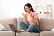 © Prostock-studio - Cherished Wish. Portrait of young woman pleading for something with crossed fingers, using laptop sitting on couch