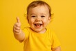 © Jelena - Adorable Toddler in Bright Yellow Outfit Giving an Enthusiastic Thumbs Up Gesture on a Cheerful Yellow Background