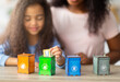 © Prostock-studio - Eco-friendly family activities. Lovely little black girl with her mother playing garbage sorting board game at home, selective focus. Adorable child putting toy trash into tiny bins