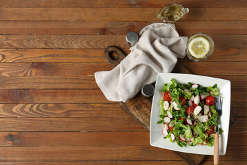 Wall Mural - Plate with tasty salad, glass of water and spices on wooden background