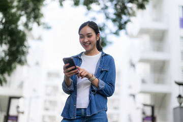 Poster - Happy asian woman using mobile phone while walking in urban city background
