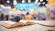 © Jinyang - Microphone resting on an open book in a bustling bookstore with blurred background of people and shelves