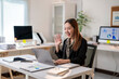 © Apichat - A woman is sitting at a desk with a laptop and smiling