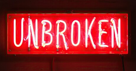 Fototapete - Bright red neon sign displays word UNBROKEN. Rectangular shape, dark background, simple design. Intense glow, captivating visual statement.