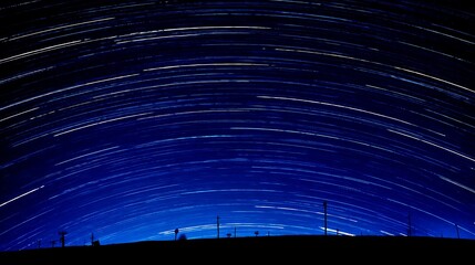 Wall Mural - Star trails above rural silhouette landscape
