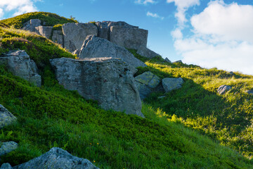 Wall Mural - pile of rock boulder on the grassy slope. alpine scenery on mount smooth in transcarpatia. blue sky 