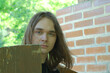 © Владимир Белобаба - Young man with long hair poses near wooden structure in lush greenery