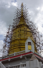 old golden yellow stupa with iron scaffolding.