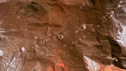 Poster - crinkled bronze foil with water droplets texture for web design and branding background