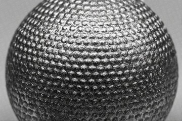 Poster - Close-up view of a textured metallic sphere illuminated with soft lighting showcasing intricate patterns and reflective surfaces