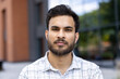 © Tetiana - Serious young indian man looking directly at the camera outdoors.