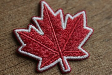 Aufkleber - Red maple leaf patch on wooden background showcasing Canadian iconography and textile craftsmanship