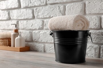 Poster - Relaxing spa setting with rolled towel in black bucket against textured brick wall