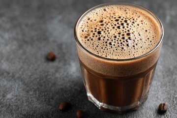 Poster - Perfectly brewed coffee served in a clear glass on a dark countertop with coffee beans nearby