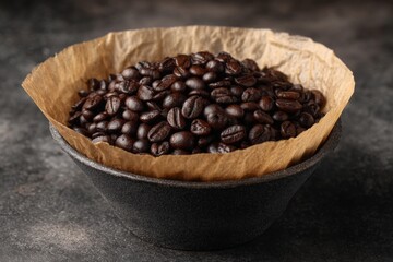 Aufkleber - Coffee beans resting in a bowl lined with paper on a textured dark surface showcasing their rich color and texture