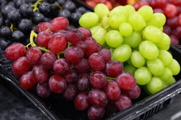 Poster - Fresh grapes in various colors displayed in a market for customers to select during a sunny afternoon