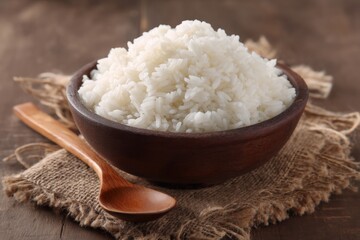 Poster - Perfectly cooked white rice served in a wooden bowl with a wooden spoon on a rustic table